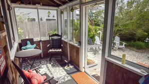 A covered patio with a table and chairs, a wooden deck, and a view of the backyard. - Walk to Private Bayside Beach! (Brewster)