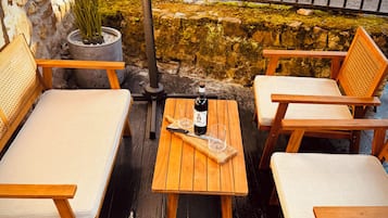 Une terrasse en bois avec une table, deux chaises rembourrées et une plante en pot.