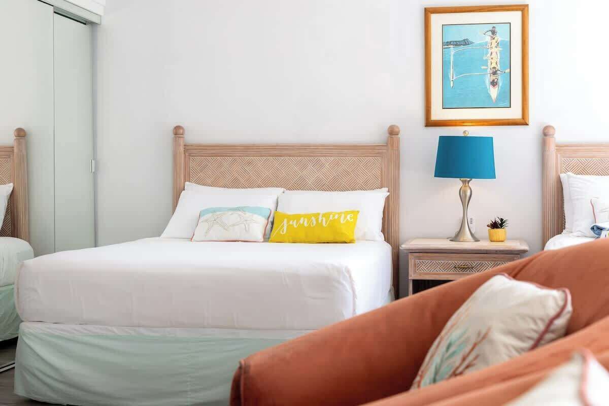 A hotel room with a bed, a nightstand with a lamp, a framed picture on the wall, and a window.