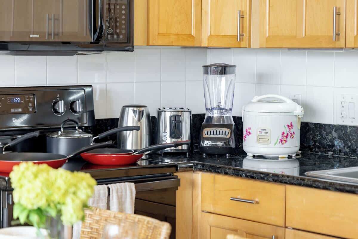 Una cocina con estufa, ollas, tostadora, licuadora y olla de cocción lenta.