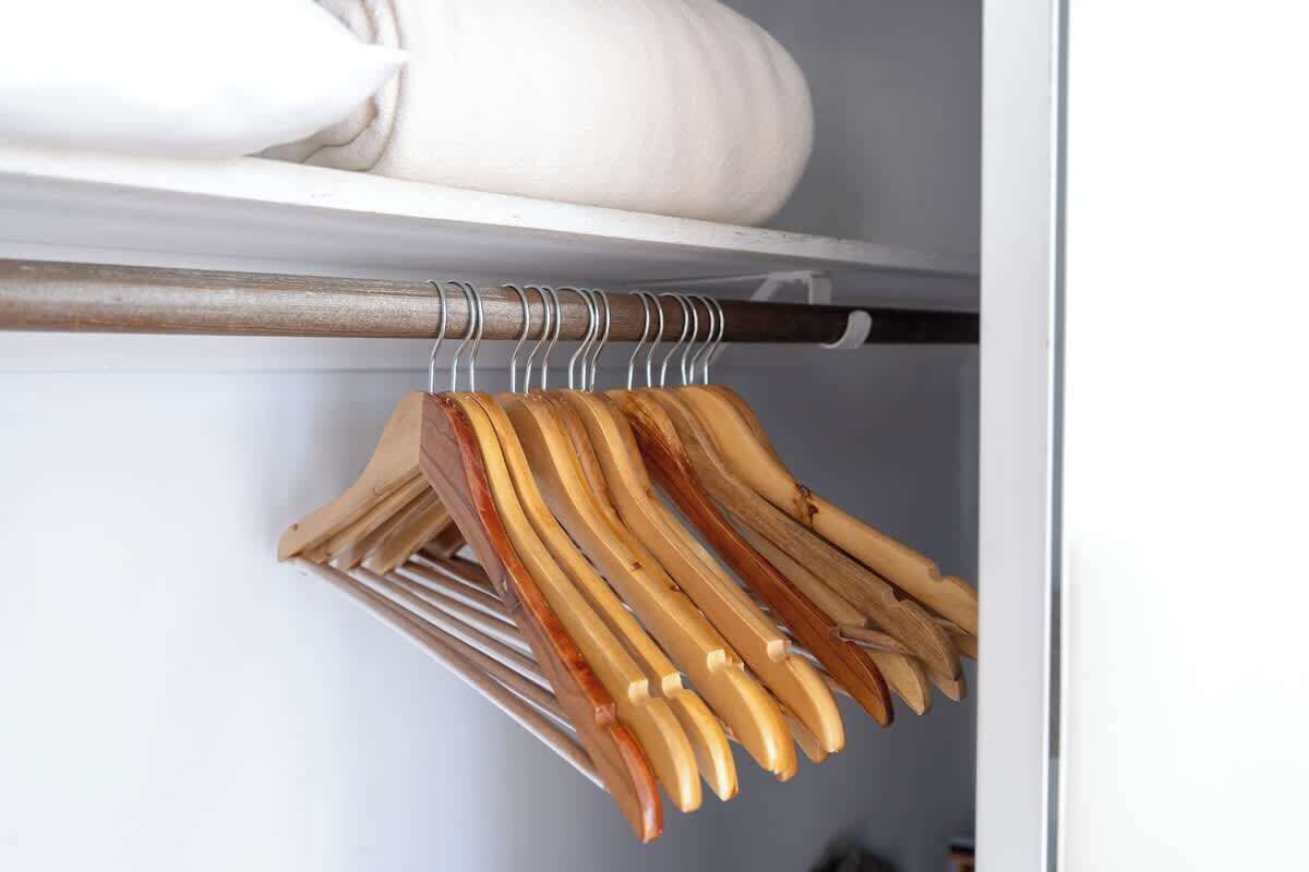 A wooden coat rack with several wooden hangers.