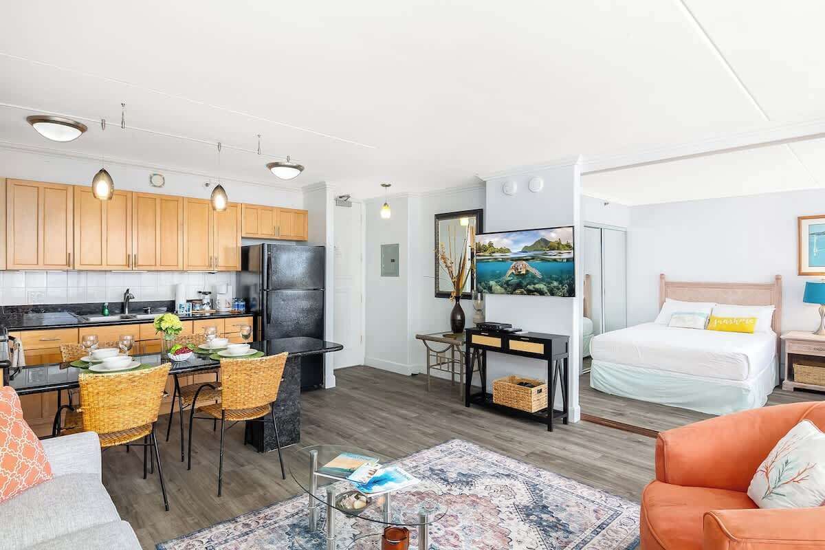 Un espace de vie compact comprenant un coin cuisine, un coin repas et une chambre avec un lit et une table de chevet.