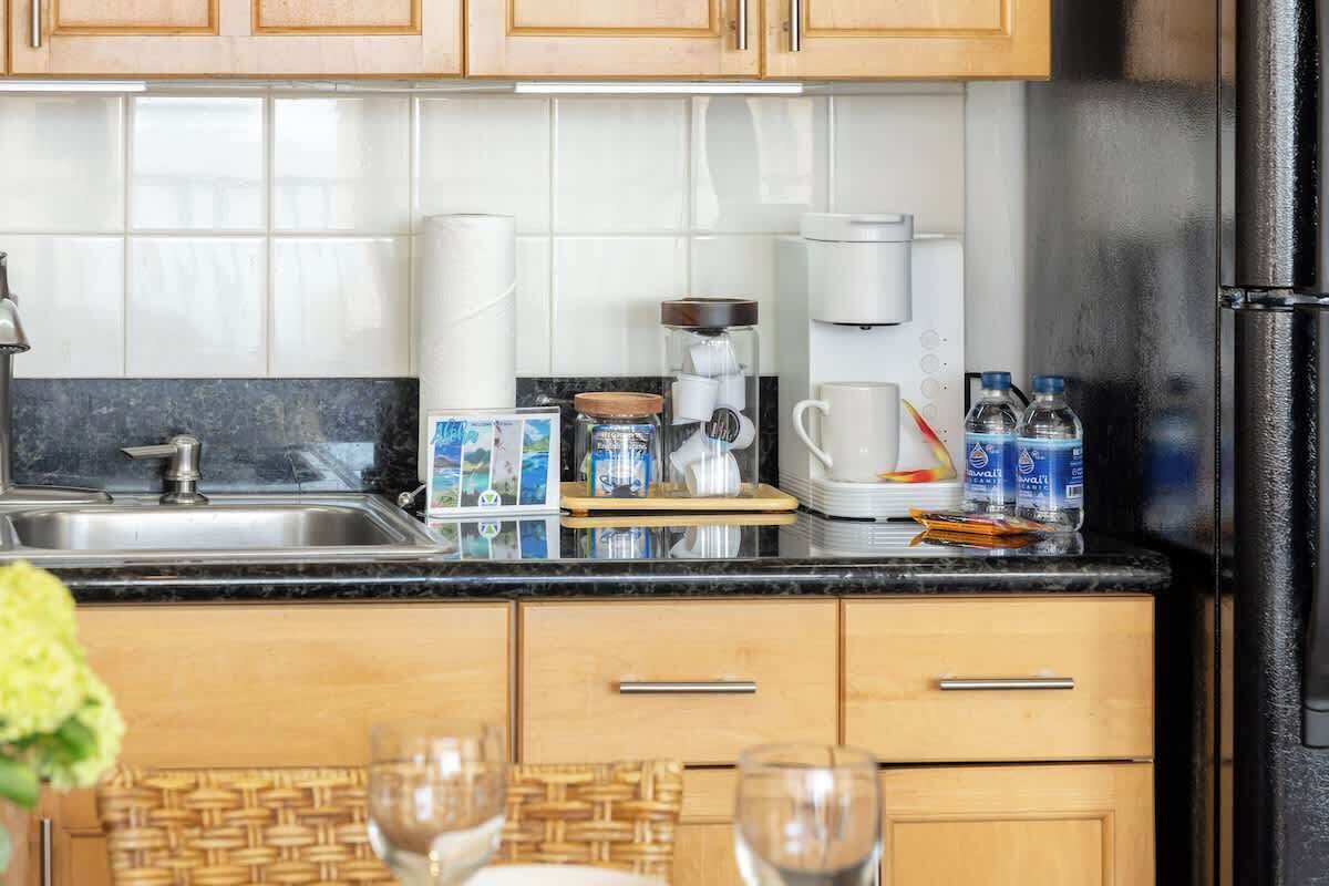 Una cocina con fregadero, encimera, armarios y refrigerador.