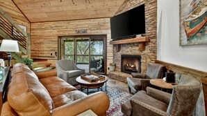 A cozy living room with leather sofas, a stone fireplace, and a large TV. - Pet Friendly, Ellijay cabin rental with a big view of the Georgia Mountains! Hot tub, outdoor fireplace (Ellijay)