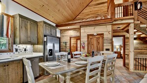 A rustic cabin interior with a dining area, kitchen, and a staircase. - Pet Friendly, Ellijay cabin rental with a big view of the Georgia Mountains! Hot tub, outdoor fireplace (Ellijay)