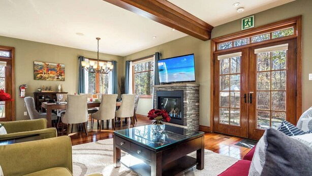 Un salón amplio con chimenea, televisor y comedor con sillas y mesa.