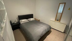 A bedroom with a bed, a nightstand, a lamp, a mirror, and a radiator. - 1br-wifi-freesnacks-freeparking-petsok-retroarcade (Newcastle-upon-Tyne)