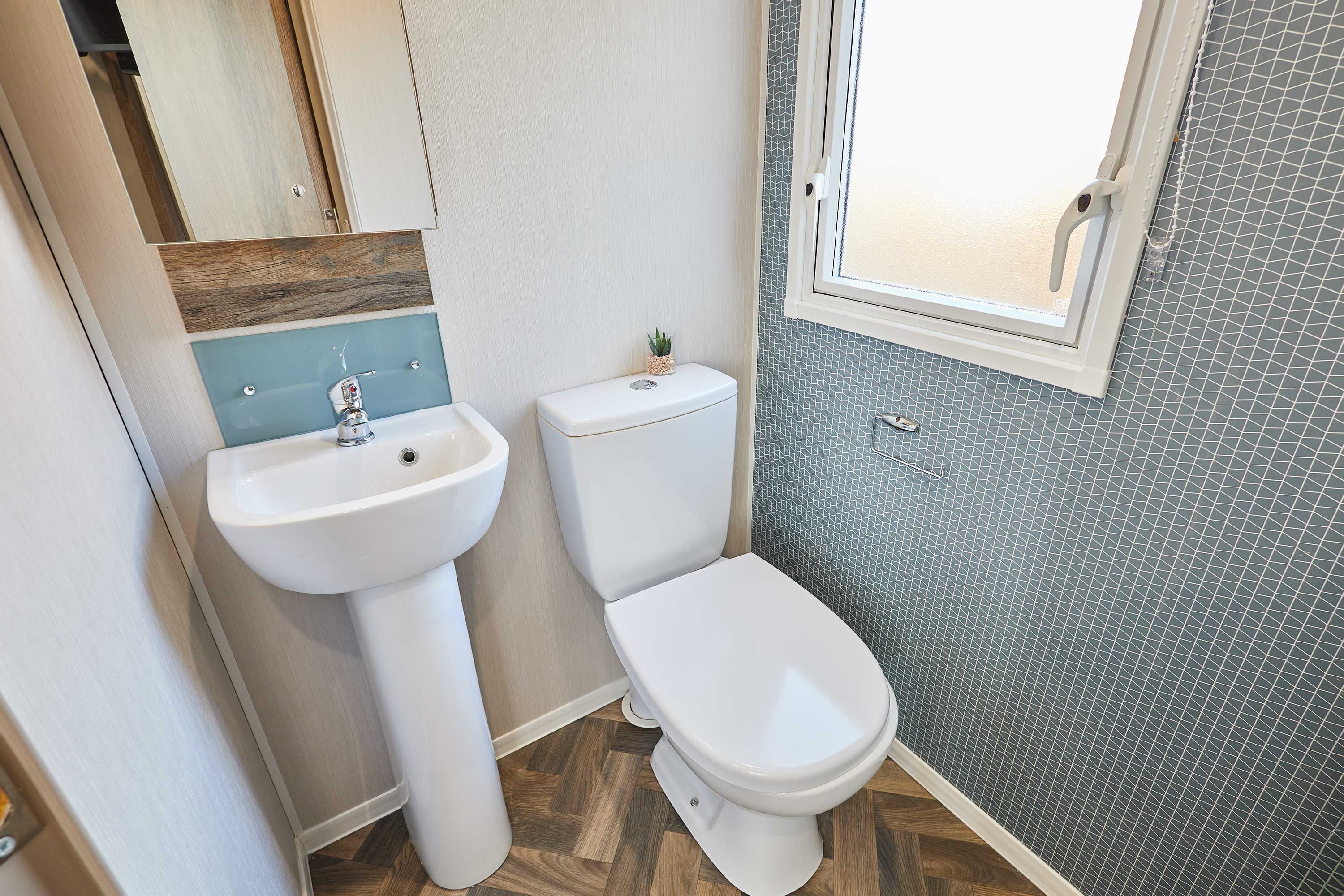 A bathroom with a white sink, toilet, and a window.