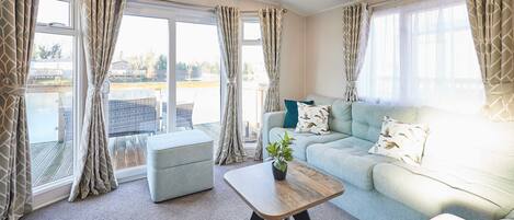 A living room with a light blue sofa, a wooden coffee table, and a grey ottoman.