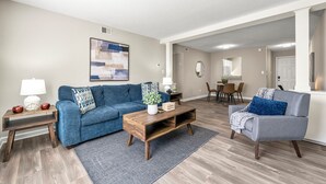 A living room with a blue sofa, a wooden coffee table, and a gray armchair. - Upper Westside Atlanta 2BR apartment with king beds, full kitchen, fast Wi-Fi, and free parking — close to dining, shopping, and MARTA. (Atlanta)