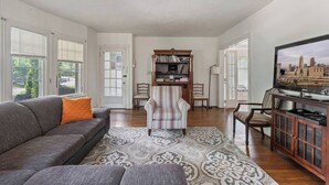 Ein Wohnzimmer mit grauem Sofa, einem gestreiften Sessel und einem Bücherregal.