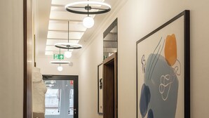 A hallway with a modern design, featuring a ceiling with skylights, a large abstract painting on the wall, and a visible exit sign. - RentPlanet - Przy Ogrodzie Botanicznym (Wroclaw)