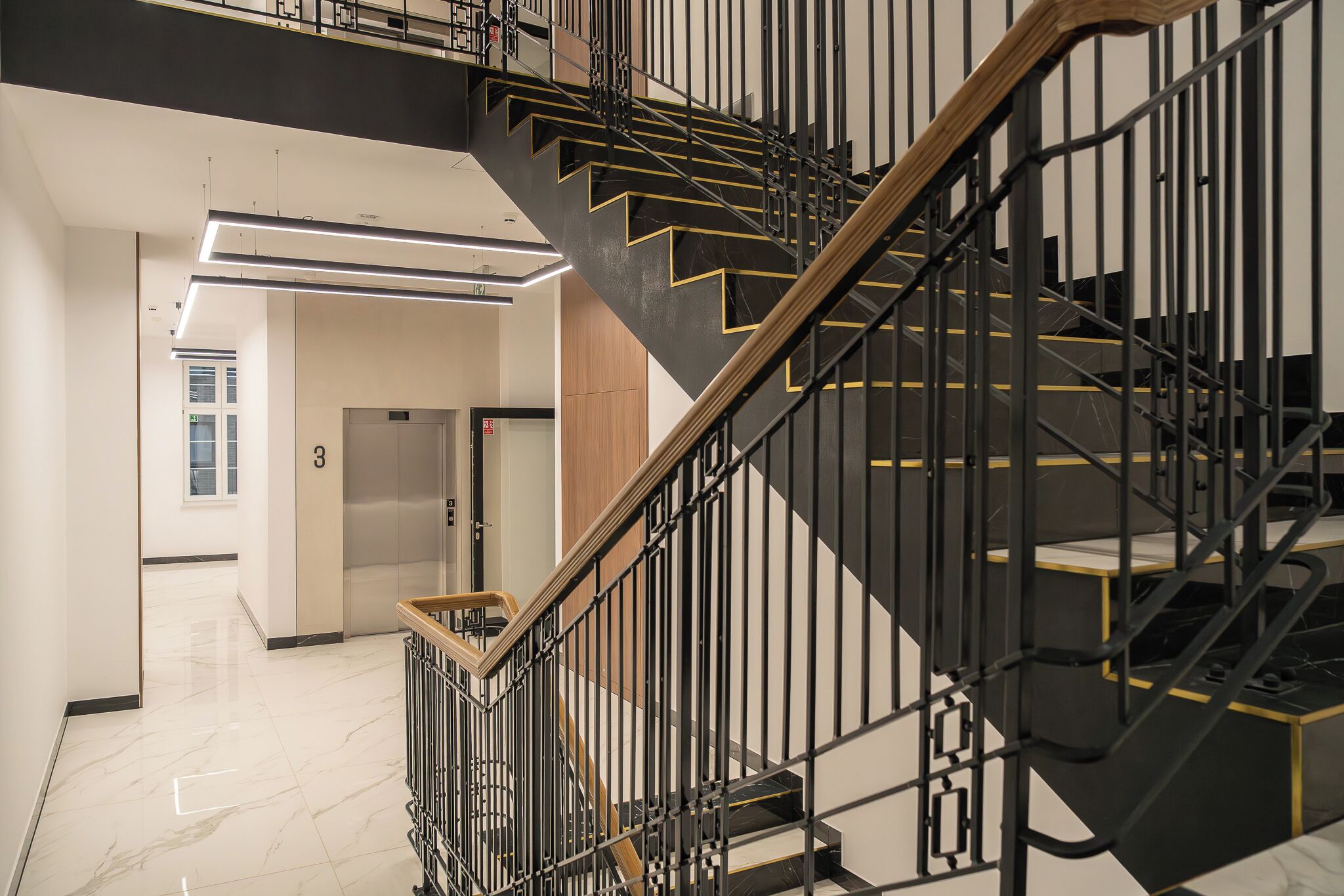 A modern interior with a staircase featuring black railings and wooden accents.