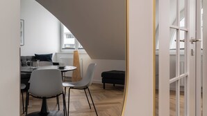A modern interior with a dining area, a sofa, a coffee table, and a window with a view of buildings. - RentPlanet - Przy Ogrodzie Botanicznym (Wroclaw)