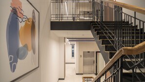 A modern interior with a staircase, a framed abstract painting, and an elevator. - RentPlanet - Przy Ogrodzie Botanicznym (Wroclaw)