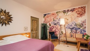 Un dormitorio con cama, una silla, una mesa y un mural floral.