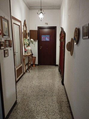 A hallway with a wooden door, a mirror, and a small table with a vase. - Naples Fuorigrotta stadium Maradona building video monitored apartment 85 sqm (Napoli)