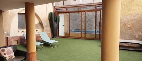 An outdoor patio with a table and chairs, a small pool, and a view of the surrounding area.
