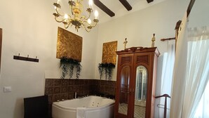 A bathroom with a freestanding bathtub, a wooden cabinet with a mirror, and a chandelier. - Studio with Jacuzzi America (Munébrega)