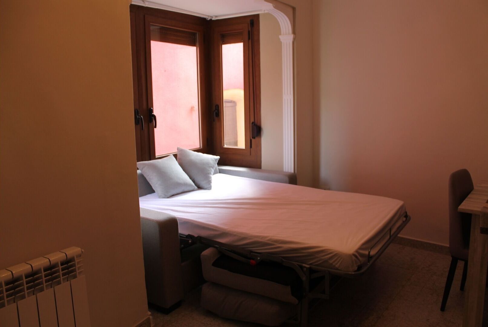 Un dormitorio pequeño con cama individual, escritorio y radiador.
