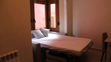 Un dormitorio pequeño con cama individual, escritorio y radiador.