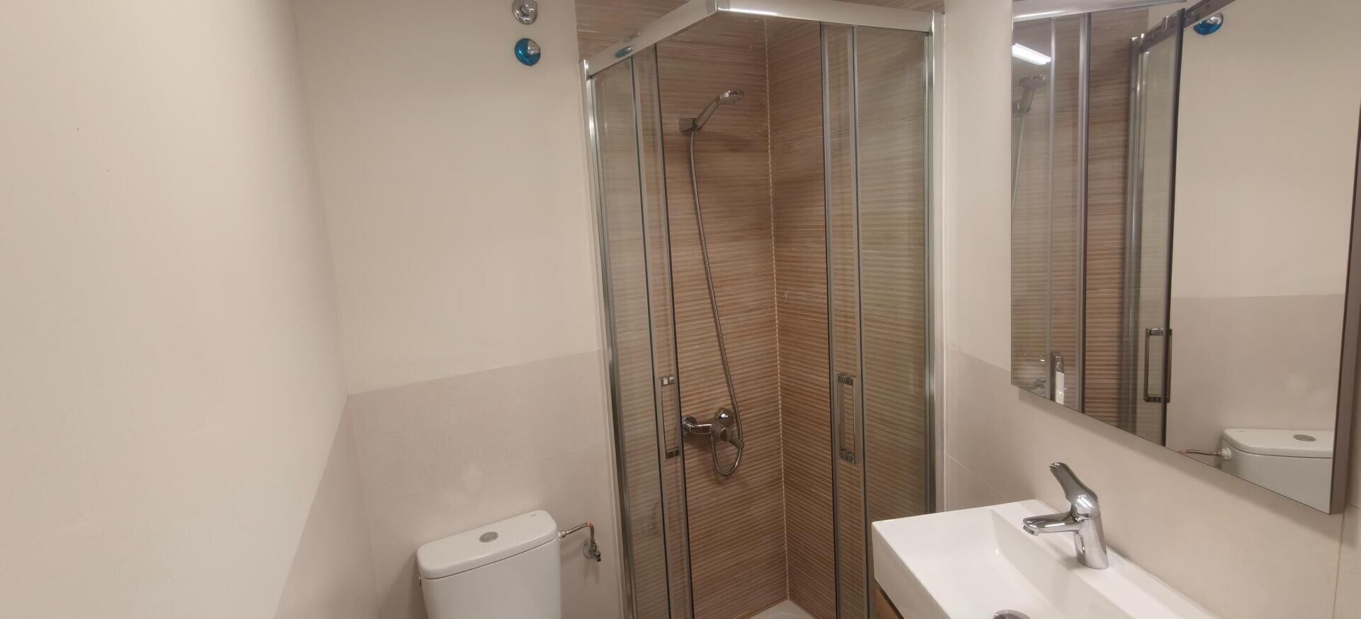 Un baño moderno con cabina de ducha de vidrio, lavabo blanco y retrete.