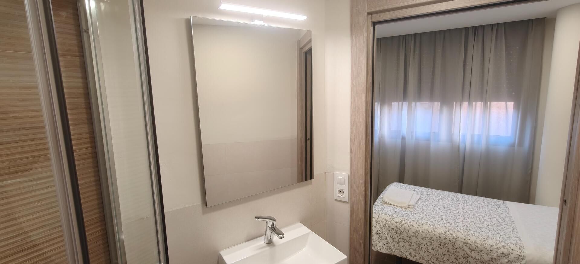 Un baño con espejo, lavamanos y zona de ducha.