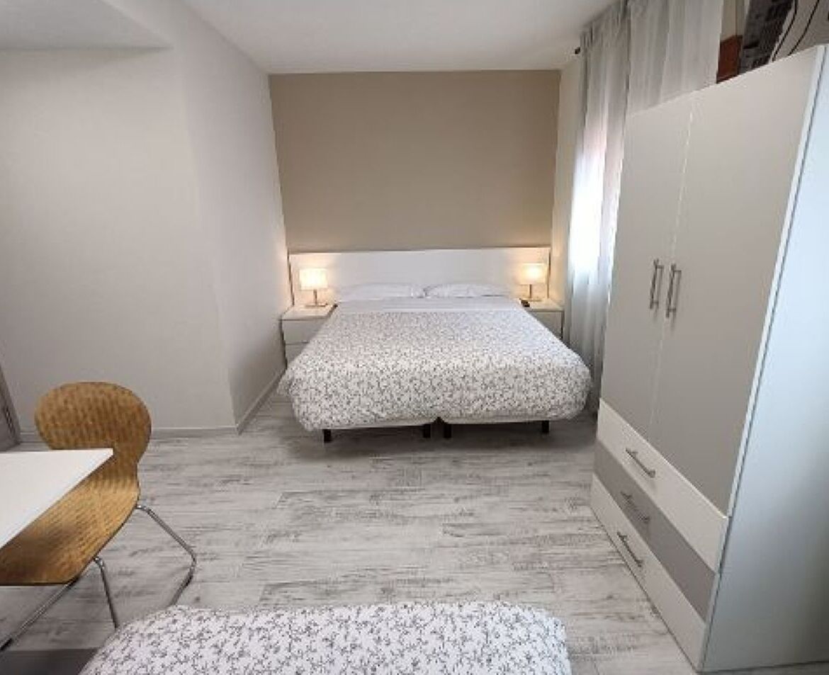 A bedroom with a bed, bedside tables, a wardrobe, and a chair.