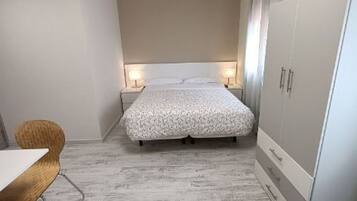 A bedroom with a bed, bedside tables, a wardrobe, and a chair.