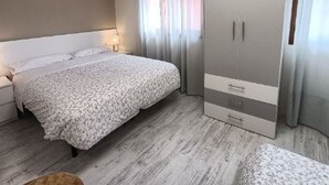 Una camera da letto con un letto, un armadio, una TV e una finestra con tende.