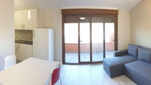 A compact living space with a kitchenette, a dining area, and a sofa.