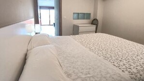 A hotel room with a bed, a desk, and a TV mounted on the wall.