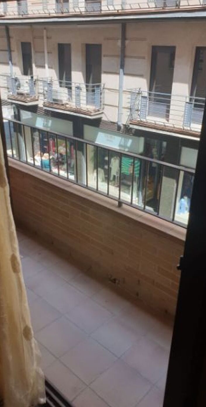 Un balcón con vista a un edificio de varias ventanas y unidades de aire acondicionado.