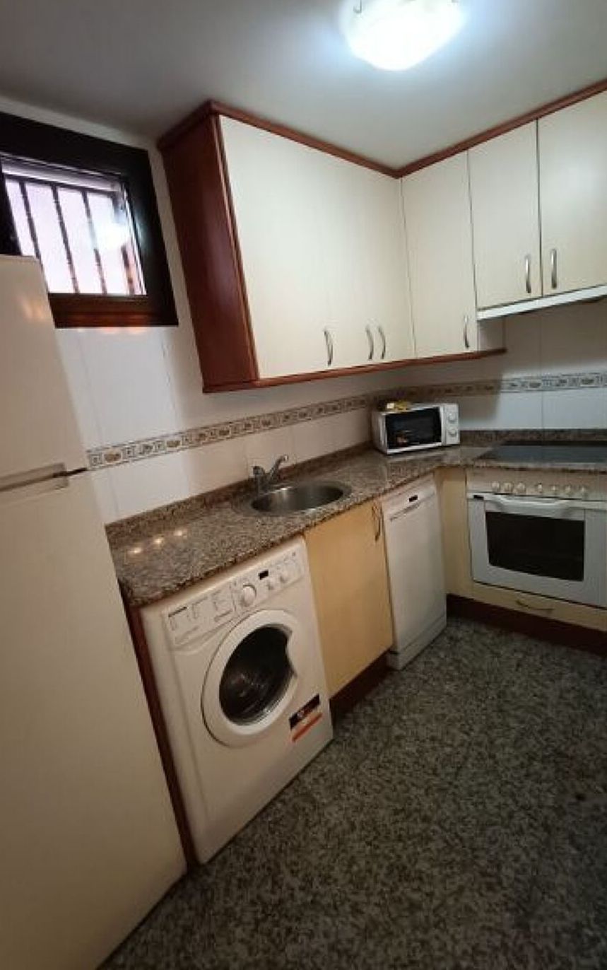 Cocina compacta equipada con lavadora, microondas y horno.