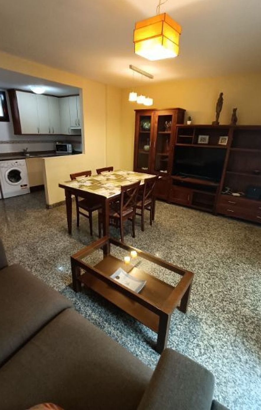 Un salon comprenant une table à manger, un canapé et une table basse. Il y a également un coin cuisine avec des appareils électroménagers et des placards.