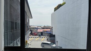 A view through a window of a parking area with several cars and a building with a red roof in the background. - Room at Weld Quay Georgetown (George Town)