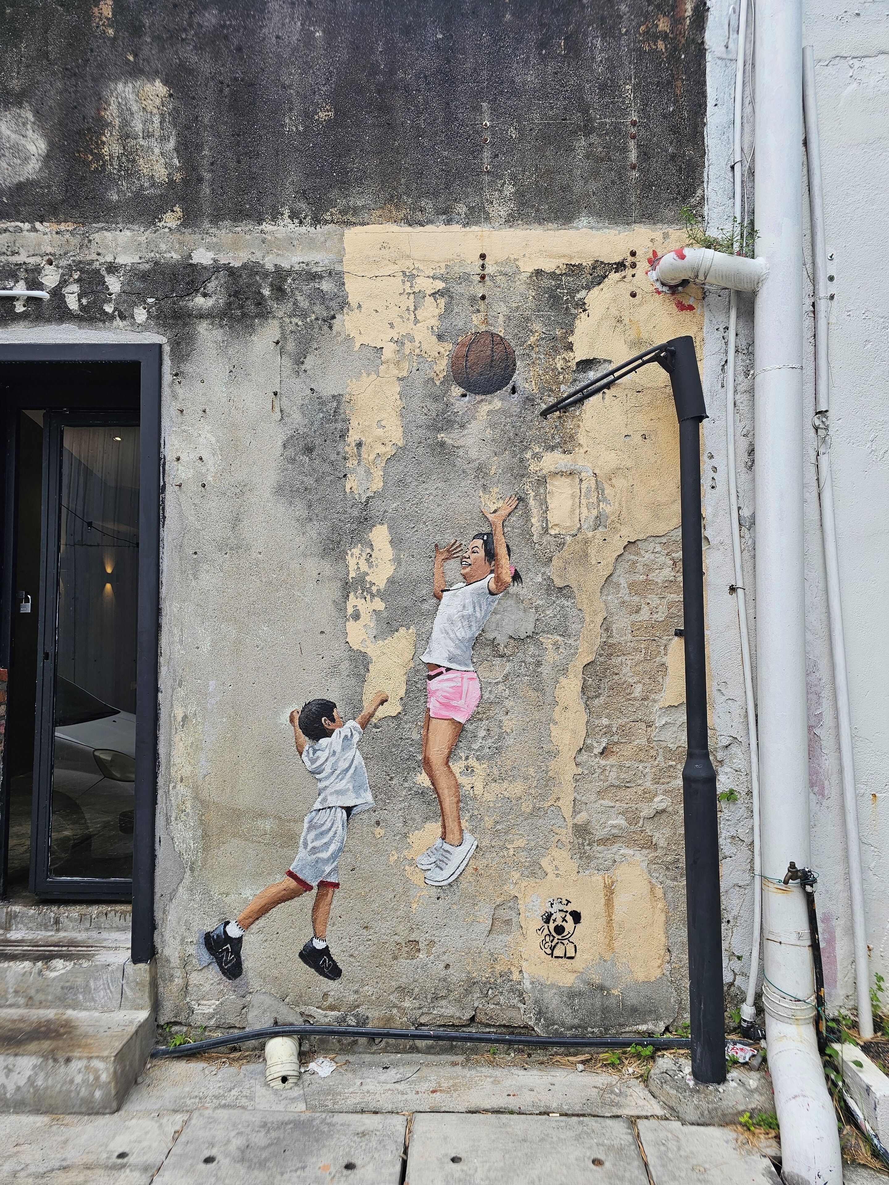 A mural of two children climbing a wall with a basketball hoop.