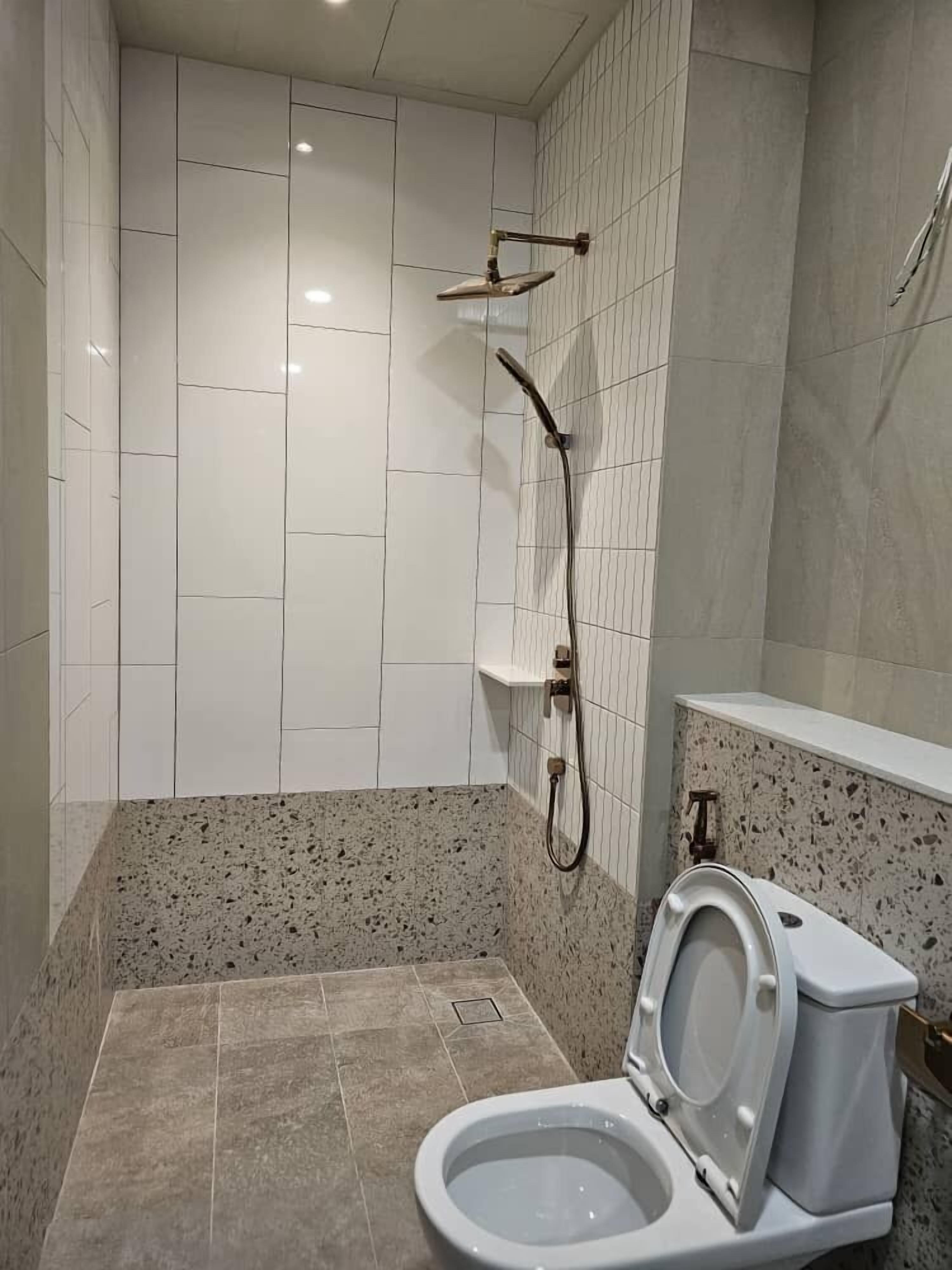 Un baño con ducha, inodoro y paredes de azulejos.
