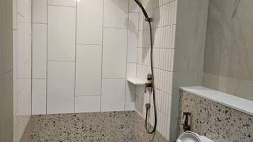 Un baño con ducha, inodoro y paredes de azulejos.