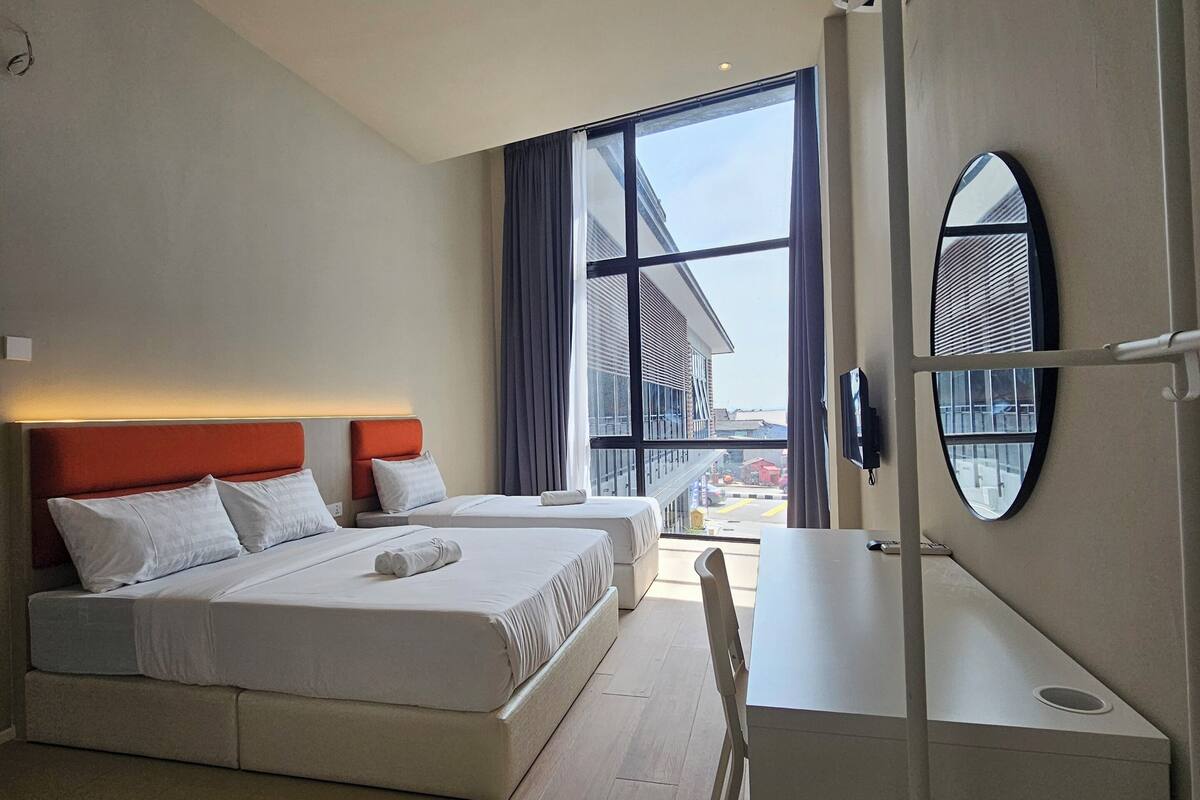 A modern hotel room with a large bed, a desk, and a view of the city.