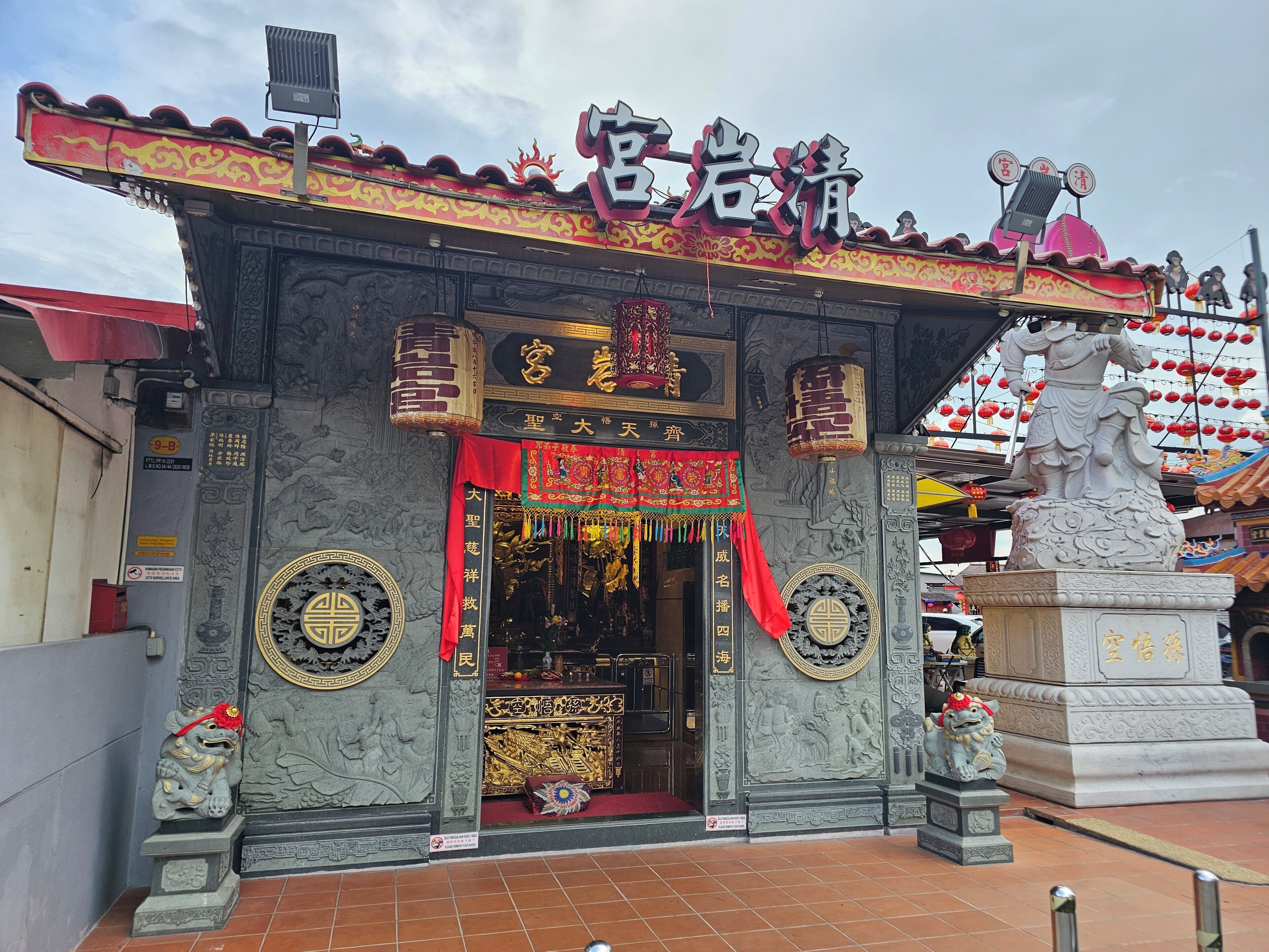 A traditional Chinese architectural entrance with ornate carvings, a red awning, and a statue of a lion.