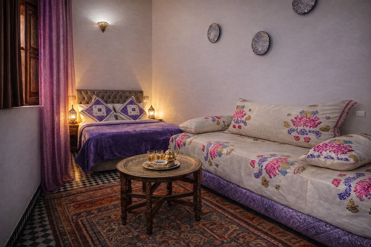 A cozy room with a bed, a sofa, a small table with a tray, and a patterned rug.