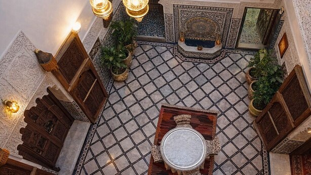 An ornate interior with a tiled floor, hanging light fixtures, and traditional wooden furniture. - Riad Rayahana Fes (Fes)