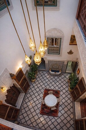 An ornate interior with a tiled floor, hanging light fixtures, and traditional wooden furniture. - Riad Rayahana Fes (Fes)