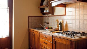 A kitchen with wooden cabinets, a gas stove, and a tiled backsplash. - Ground floor apartment with one double bedroom (Toscana)