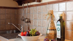 A kitchen with a sink, a bowl of vegetables, a bottle of olive oil, and a cutting board. - Ground floor apartment with one double bedroom (Toscana)