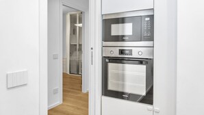 A modern kitchen with a built-in oven and microwave, a wooden floor, and a white interior.