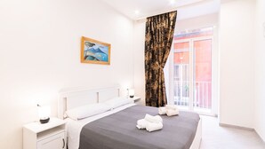 A bedroom with a bed, bedside tables, a painting, and a view of the outside. - Dimora Sergente Maggiore By DomusExtra (Naples)