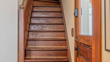 A wooden staircase with a handrail and a door with a window on the right side.