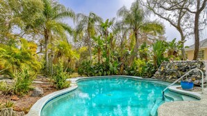 A swimming pool surrounded by tropical plants and a stone wall. - Casa Ola Escape (St. Augustine)